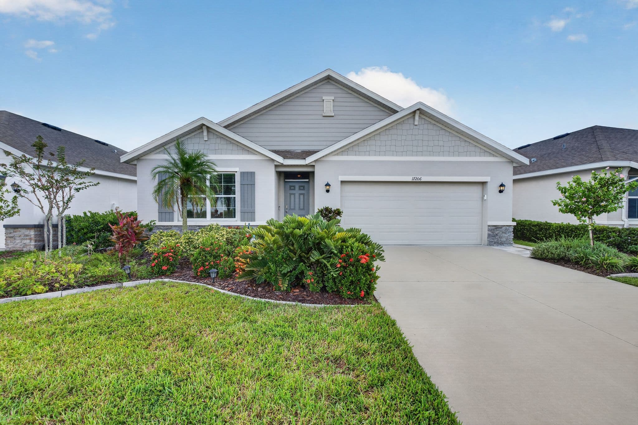 Front of the home in daylight with shake-siding gables, a two-car garage and a manicured lawn