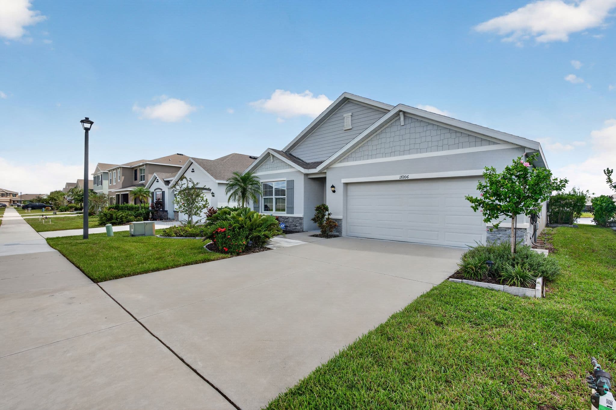 Street view of the home and wide driveway along a sidewalk lined with neighboring homes