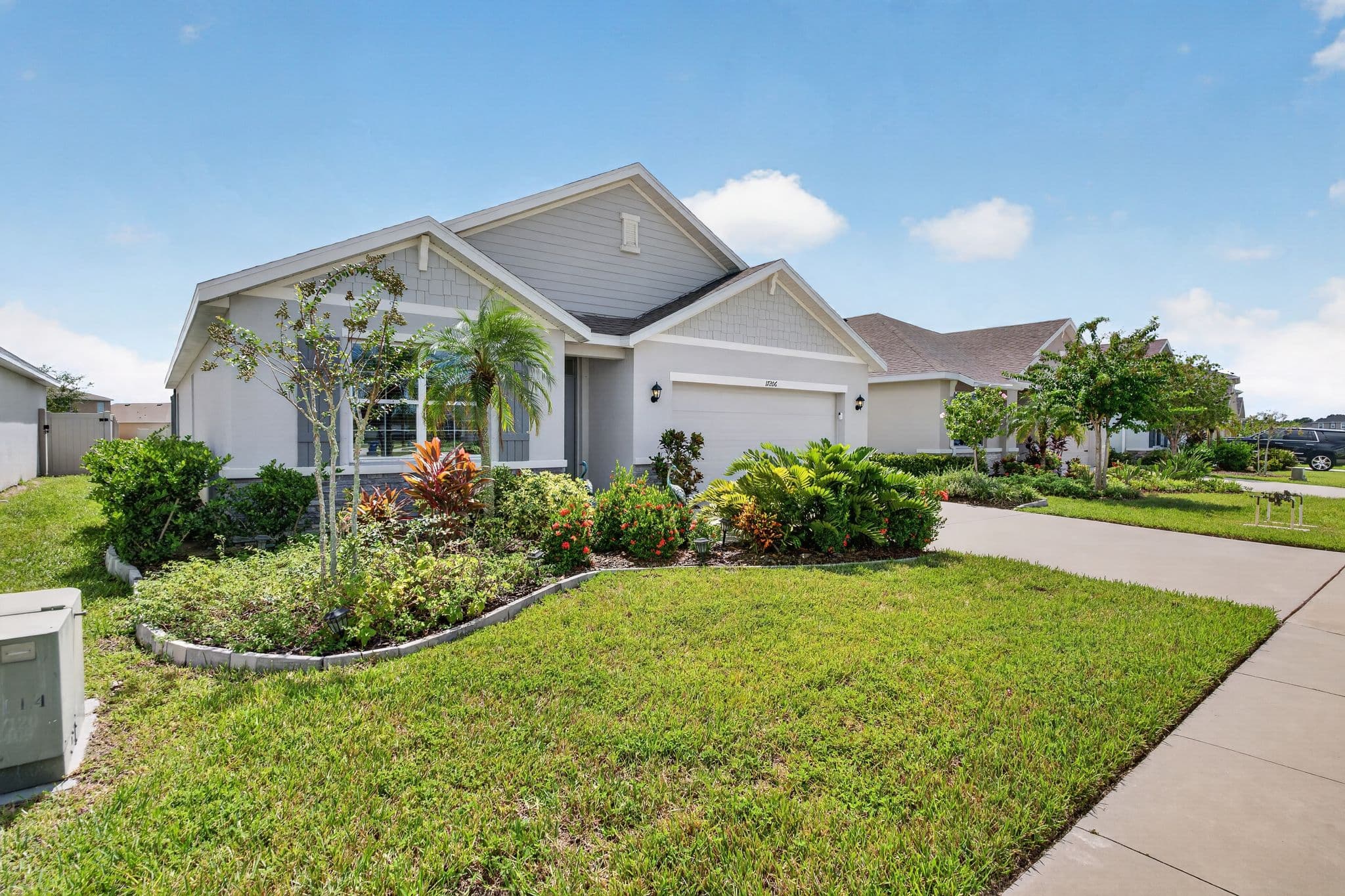 Angled view of the home showing layered tropical garden beds and a lush front lawn